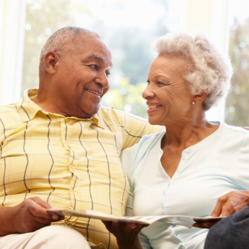 An older african american couple sitting together smiling.