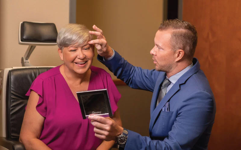 Dr. Friedrichs at Collins Vision is examining a patients eyelids at her blepharoplasty consultation