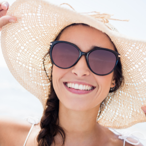 Woman happy on beach with sunglasses and hat in southwest Florida Collins Vision